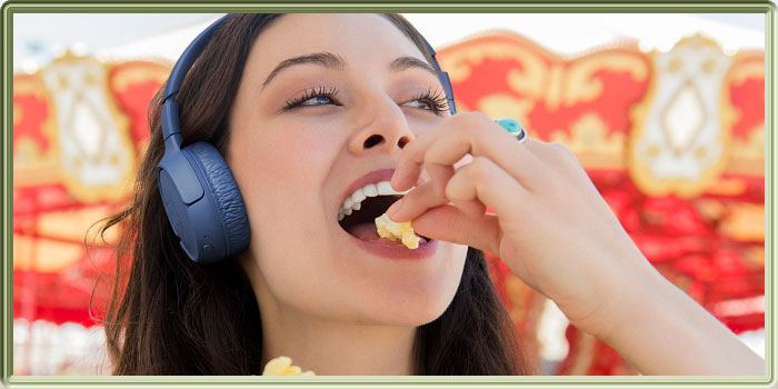 Visuel du Casque JBL Tune 570BT portée par une jeune femme mangeant du popcorn